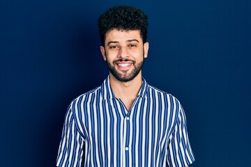 Young arab man with beard wearing casual striped shirt with a happy and cool smile on face. lucky person.