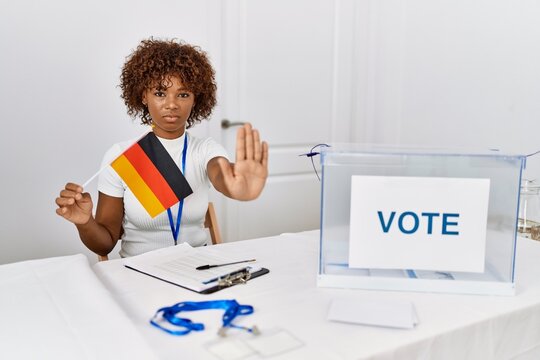 Young african american woman at political campaign election holding germany flag with open hand doing stop sign with serious and confident expression, defense gesture