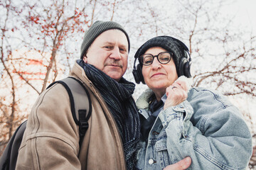 an elderly couple on the street laughing and hugging, it's cold