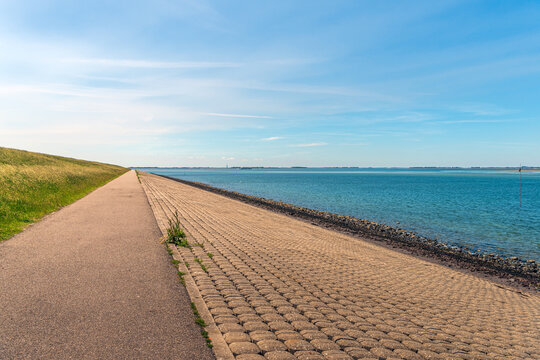 Dike along the shore of the former Oosterschelde estuary near the village of Sint-Annaland (Tholen) in the Dutch province of Zeeland. It's a sunny day in springtime with a bright blue sky.