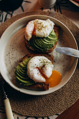 Sandwich with avocado and boiled egg top view. Avocado toast with poached eggs and spices. Breakfast with healthy fats and omega 3.
