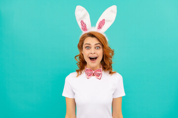 amazed easter girl in bunny ears and bow tie on blue background