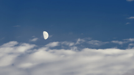 A crescent moon flying across the evening dark sky. It reflects sunlight and so far is the only visible object in the sky.