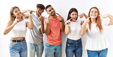 Group of young friends standing together over isolated background smiling cheerful showing and pointing with fingers teeth and mouth. dental health concept.