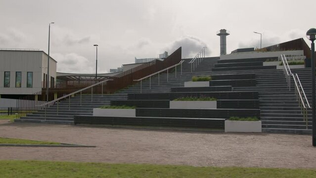 Stylish empty staircase with flowerbeds near large shopping mall building under cloudy sky on gloomy spring day