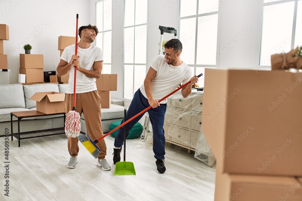 Sticker Two hispanic men couple cleaning and dancing at new home