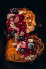dessert with cranberry jam, almond flakes and blueberries top view. useful dessert in a black dish macro photo. details of dessert with red jam and berries close-up.