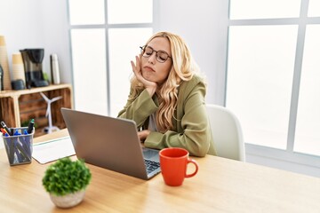 Beautiful blonde woman working at the office with laptop thinking looking tired and bored with depression problems with crossed arms.