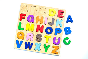 English alphabet made of square wooden tiles with the English alphabet scattered on white background.