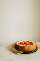 ready-made quiche with cherry tomatoes on a plate with baking paper. pie with shortcrust pastry on a white background. cottage cheese pie with tomatoes on a marble table.