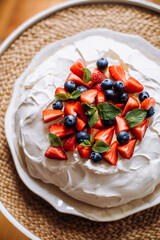 pavlova dessert with strawberries, blueberries and mint leaves top view. pavlova garnished with fresh strawberries, blueberries and mint. whipped egg whites dessert.