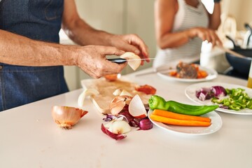 Middle age hispanic couple cooking at kitchen