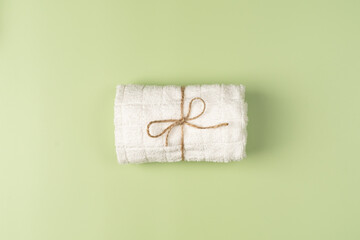 Flat lay, clean fresh white towel on a light green background.