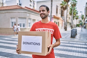 Handsome hispanic man holding donations box outdoors