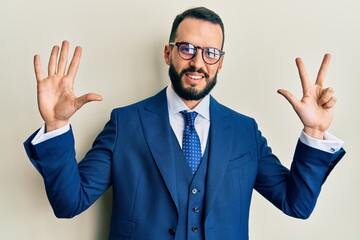 Young man with beard wearing business suit and tie showing and pointing up with fingers number eight while smiling confident and happy.