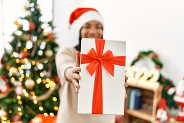 Hispanic brunette woman holding christmas present at home