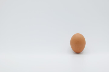 A brown egg placed upside down on a plain white background.