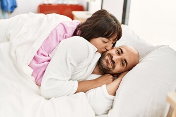 Young hispanic couple smiling happy lying on the bed at bedroom.