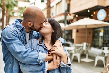 Young hispanic couple kissing and hugging at the city.