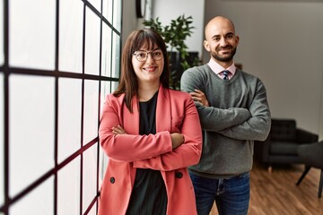 Two hispanic business workers smiling happy with arms crossed gesture standing at the office.