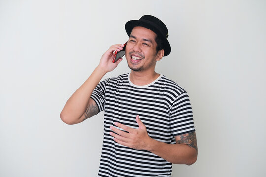 Tattooed Asian man smiling happy when talking on the phone