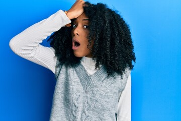 African american woman with afro hair wearing casual winter sweater surprised with hand on head for mistake, remember error. forgot, bad memory concept.