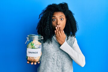 African american woman with afro hair holding savings jar with south african rands money covering...