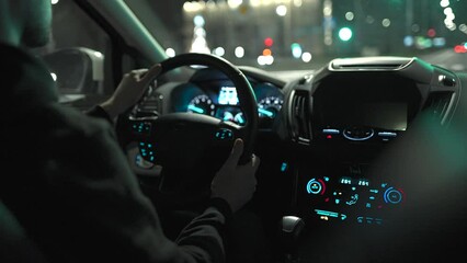 Man driving car through the streets of night city. View from the back seat of the car.