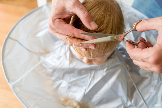 Man's Hands Doing Toddler Haircut With Hairdresser Scissors At Home. Baby Boy Hair Cut Diy