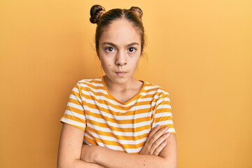 Beautiful brunette little girl wearing casual striped t shirt skeptic and nervous, disapproving...