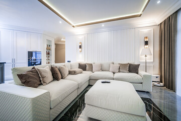 living room in a light minimalist design. White sofa with white and brown pillows.
