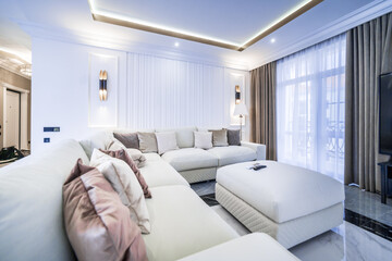 living room in a light minimalist design. White sofa with white and brown pillows.