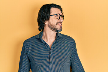 Middle age caucasian man wearing casual clothes and glasses looking to side, relax profile pose with natural face and confident smile.