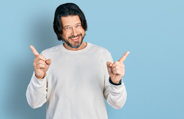 Middle age caucasian man wearing casual clothes smiling confident pointing with fingers to different directions. copy space for advertisement