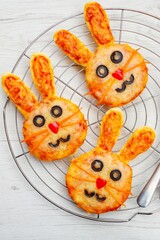 Mini easter bunny pizzas on cake rack with white wood background.Art food idea for kids Easter's...