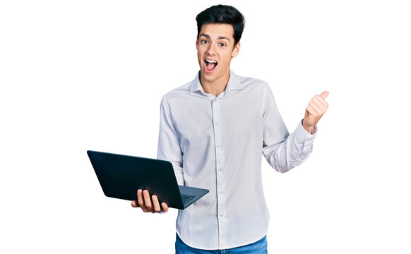 Young hispanic business man working using computer laptop pointing thumb up to the side smiling happy with open mouth