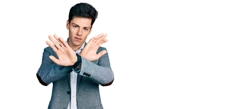 Young hispanic man wearing business clothes rejection expression crossing arms doing negative sign, angry face