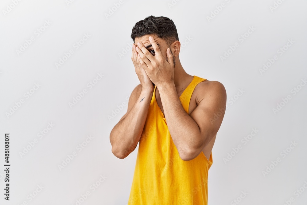 Sticker young handsome man with beard standing over isolated background with sad expression covering face wi