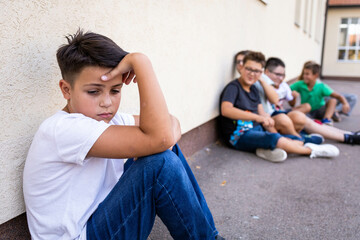 Group of schoolboys bullying a sad and upset looking boy. - obrazy, fototapety, plakaty