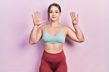 Young hispanic girl wearing sportswear showing and pointing up with fingers number nine while smiling confident and happy.