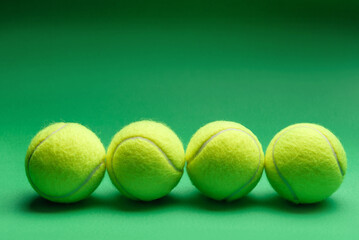tennis balls lie in a row on a green background.