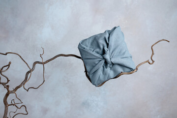 A furoshiki wrapped box on tree branch in front of the wall, sustainable packaging concept