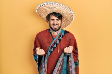 Young hispanic man holding mexican hat excited for success with arms raised and eyes closed...