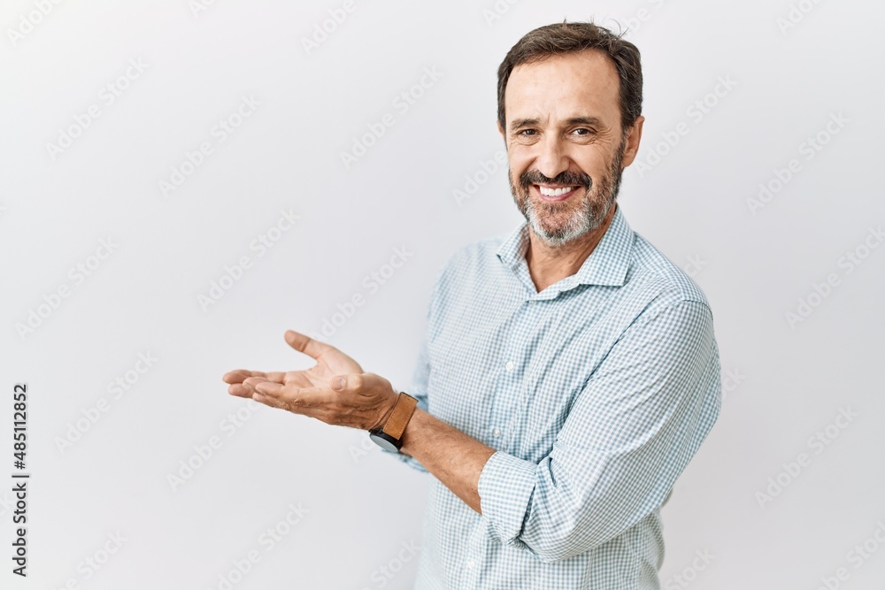 Wall mural middle age hispanic man with beard standing over isolated background pointing aside with hands open 