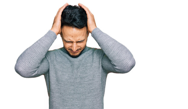 Young arab man wearing casual clothes suffering from headache desperate and stressed because pain and migraine. hands on head.