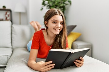 Adorable girl smiling confident reading book at home