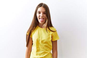Young brunette teenager standing together over isolated background sticking tongue out happy with...