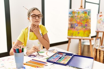 Young brunette teenager at art studio touching painful neck, sore throat for flu, clod and infection
