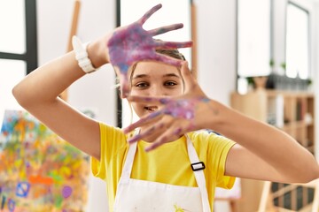 Adorable girl smiling confident showing painted palm hands at art studio