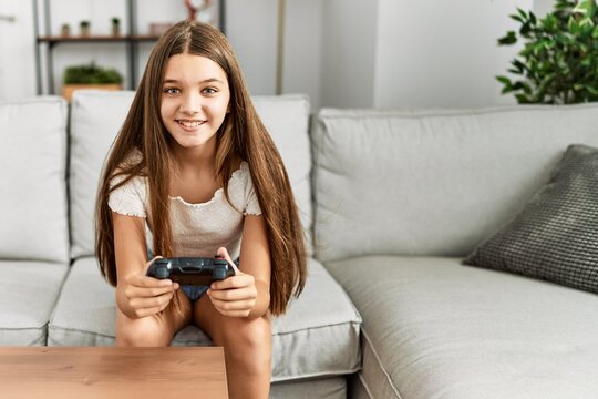 Adorable girl smiling confident playing video game at home